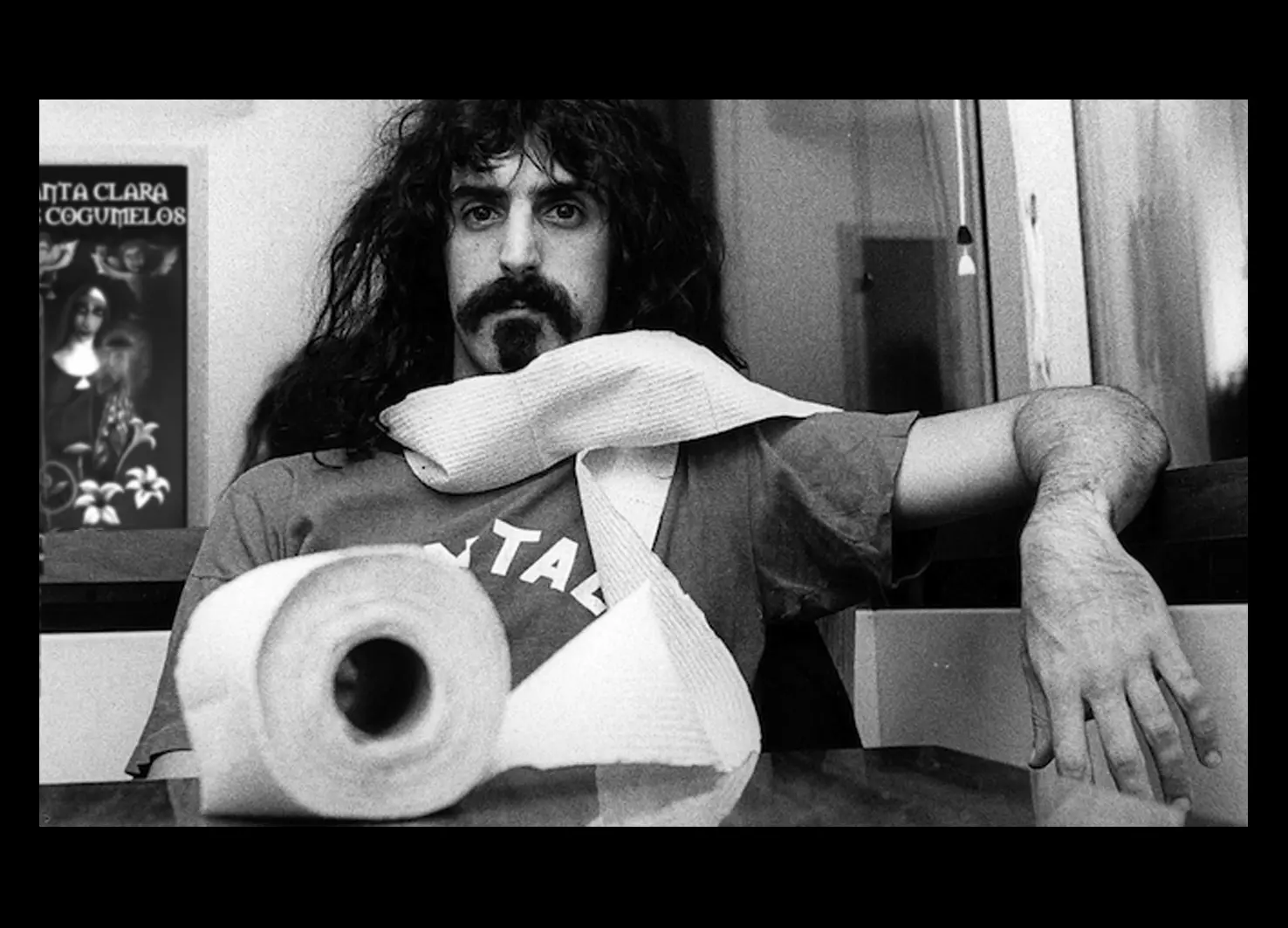 Frank Zappa com um manifesto SCDC ao fundo